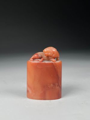une figurine en jade orange représentant un singe perché sur un rocher