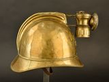 brass helmet mounted on a metal pole on a black background