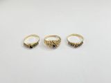 three gold rings on a white surface