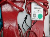 pair of red leather sandals with a price tag on top of them