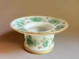 a green and white bowl with a gold rim on a table