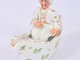 a figurine of a man in a boat on a white surface