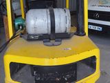 a yellow forklift with a keg on top of it in a garage