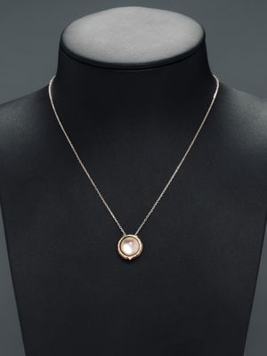 un collier en or avec un pendentif en perle autour du cou d'un mannequin