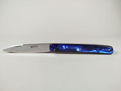 un couteau au manche bleu posé sur une surface blanche
