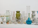 many different colored glass vases on a white surface