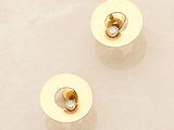two pairs of gold and diamond stud earrings sitting on a white surface