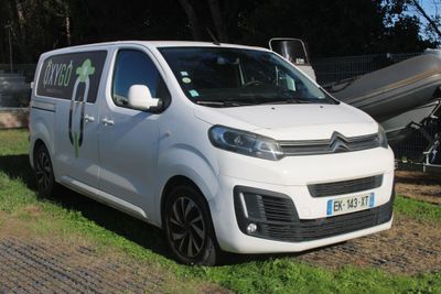 une petite camionnette blanche garée sur l'herbe, à côté d'un bateau