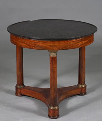 une table ronde avec un plateau en marbre noir reposant sur un piètement en bois
