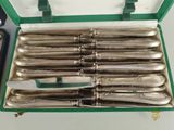 silverware in a green case on a table with a pair of scissors