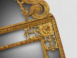 a mirror that has a gold frame with flowers on it