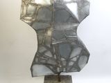 sculpture en argent et noir représentant un torse, posée sur un socle en marbre