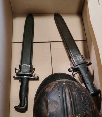 a box with two knives and a helmet inside of it