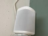 une enceinte blanche fixée au mur, à côté d'un mur blanc