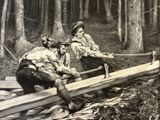 a black and white photo of two men working in the woods