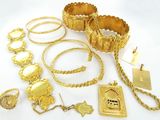 Plusieurs bijoux en or sont disposés sur une surface blanche