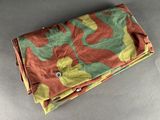 a green and orange camouflage cloth with a button on it
