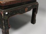 an old wooden table with a black and red design on the top