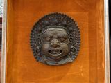 a bronze head of a man in a wooden frame