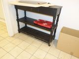 une table noire sur laquelle se trouve un plateau rouge, et une boîte posée par terre
