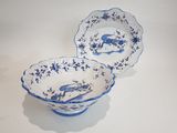 two blue and white bowls with a bird on them sitting on a table