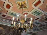 a chandelier in the middle of a room with paintings on the walls