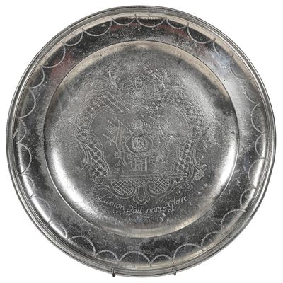 une vieille assiette en argent ornée d'un motif sur fond blanc