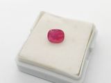an image of a red ruby stone sitting on a white surface