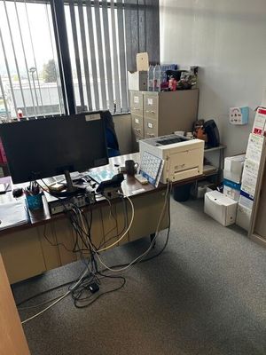 un bureau avec un ordinateur et une imprimante dans un coin de la pièce