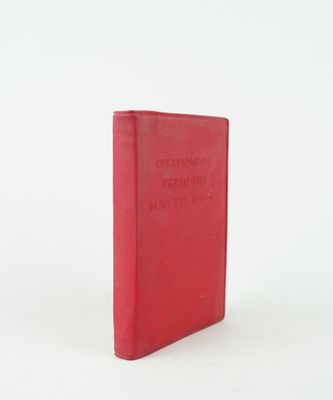 un vieux livre rouge posé sur une surface blanche