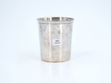an old silver cup sitting on a white surface with a sticker on it
