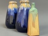 trois vases bleus et jaunes posés les uns à côté des autres sur une surface grise