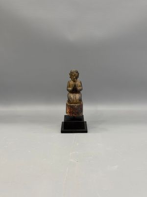 a small bronze statue of a woman sitting on a rock