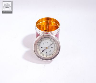 a clock sitting in a glass container on a white surface