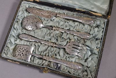 de l'argenterie dans un coffret posé sur une table recouverte d'une nappe bleue
