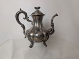 a silver tea pot sitting on a glass table