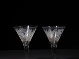 two empty wine glasses sitting on a table with a black background