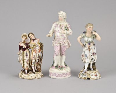 three porcelain figurines of a man and a woman, one of which is holding a child