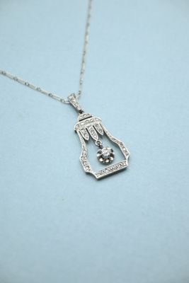 a close up of a silver necklace with a bird in a cage
