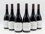 six bouteilles de vin sont alignées sur une surface blanche