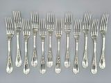 six fourchettes et six couteaux sont disposés en rangée sur une table