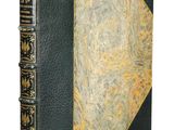 an old book with a black cover and gold trim