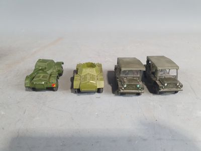 four toy army vehicles are lined up in a row on a white surface