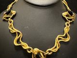 a gold necklace on a mannequin display with a black background