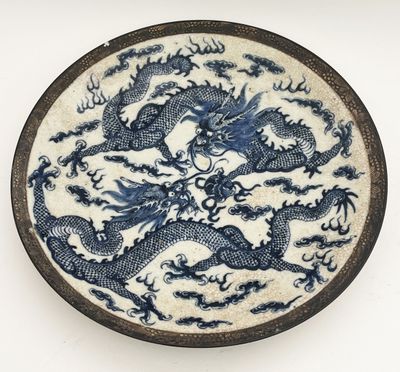 assiette bleue et blanche ornée d'un motif de dragon sur fond blanc