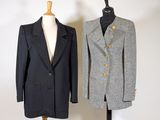 two coats on a mannequin stand in front of a white wall