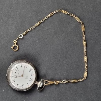 a silver pocket watch on a chain on a table