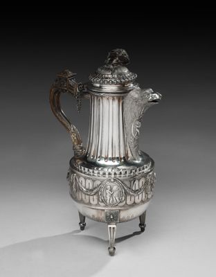 une cafetière en argent avec une anse en forme de dragon, posée sur un socle