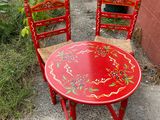 une table rouge et deux chaises posées par terre