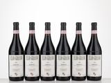 six bottles of red wine are lined up on a table
